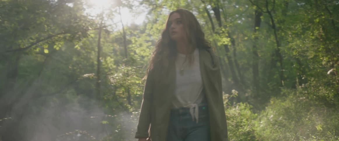 A woman walks in the woods on a sunny day