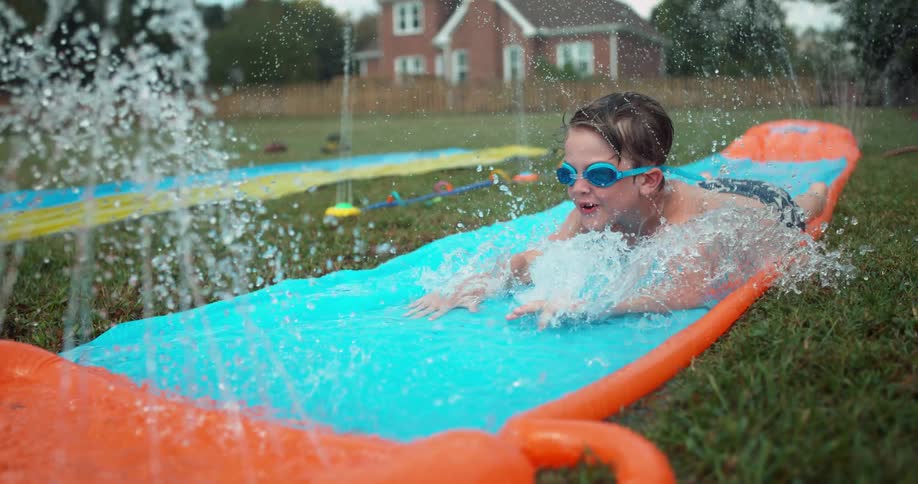 Boy slides down a slip n' slide on a sunny day