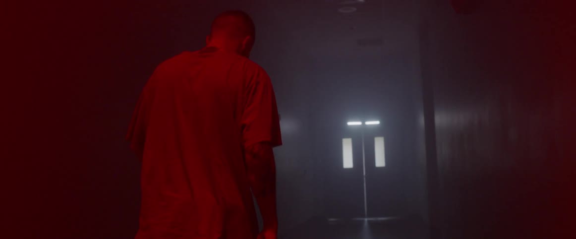 Man in a t shirt walks down a building hallway