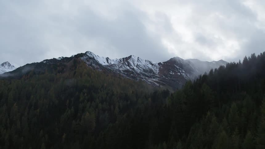 The forested hills in the snow capped mountain range