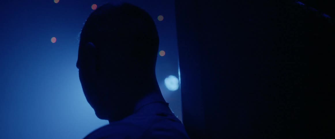 A young man standing in a foggy room with bright flashing lights