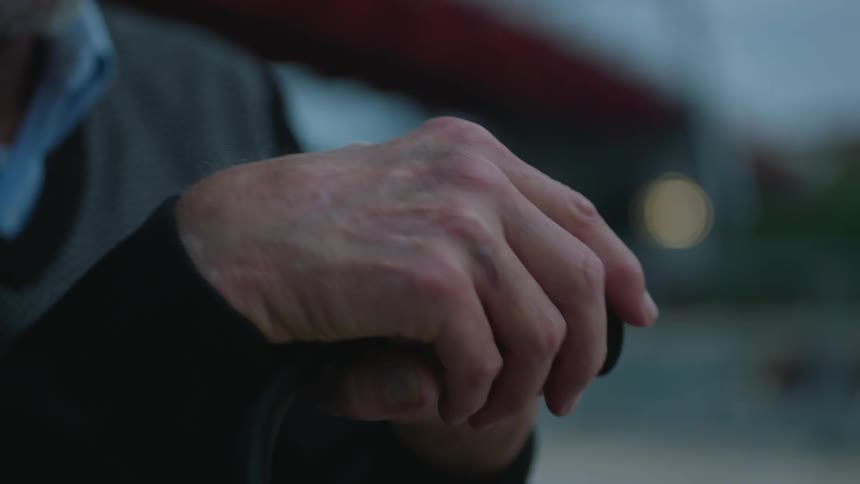 A man grabs the top of his cane