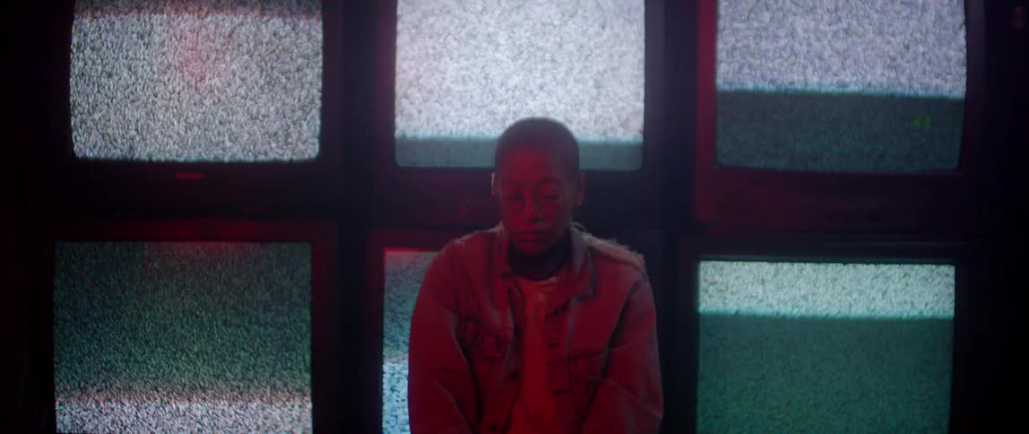 A person is sitting still in front of tvs playing static