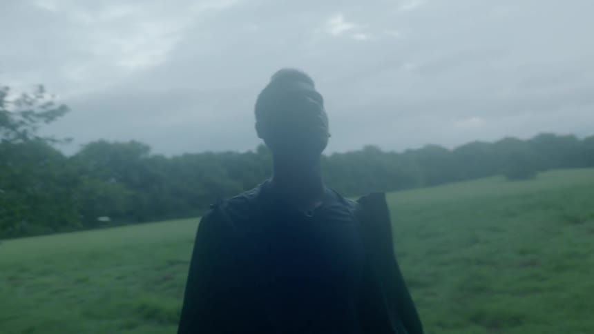 Man looks around at the edge of a forest