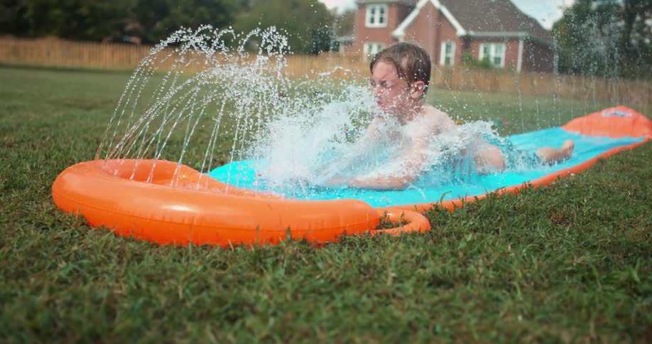 A child slides down a slip 'n slide in a backyard