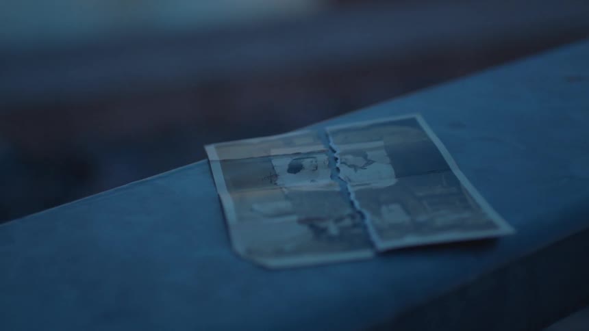 A torn photograph sits on a ledge