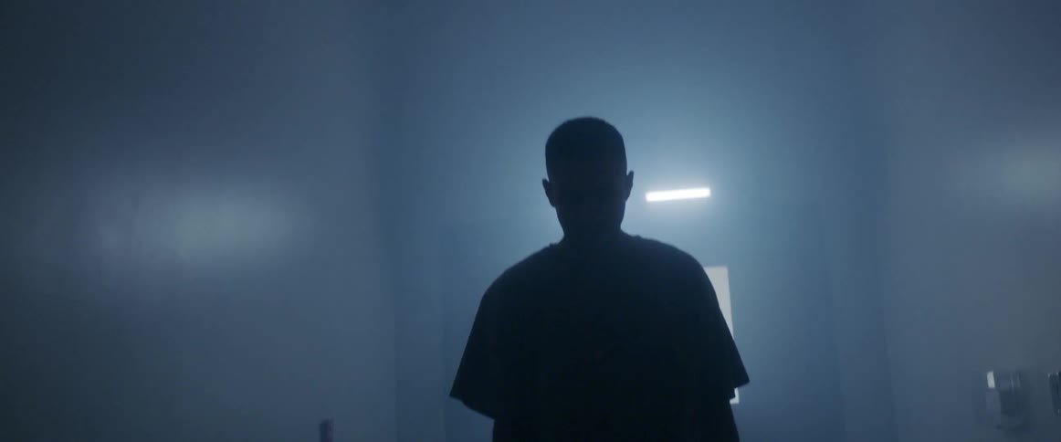 A man walking through a poorly lit foggy hallway