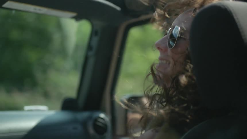 Woman rides in topless vehicle as her curly hair blows in the wind