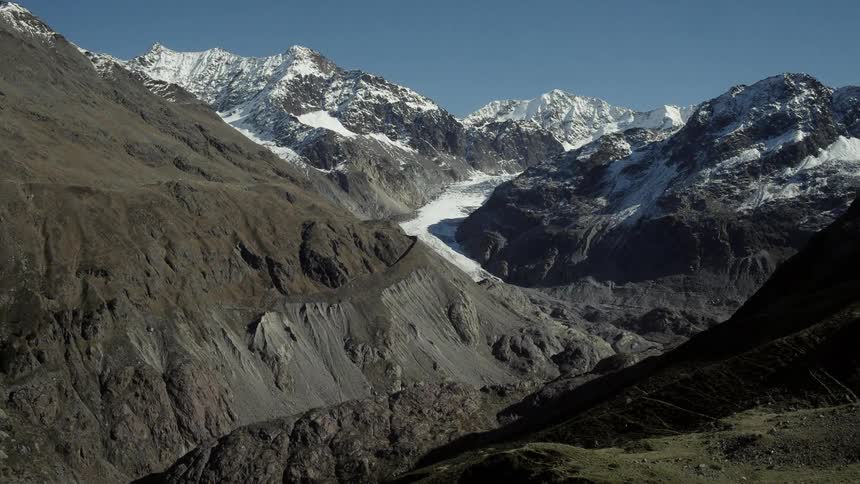 Snow covers the peaks in a vast mountain range but doesn't reach down to the valley