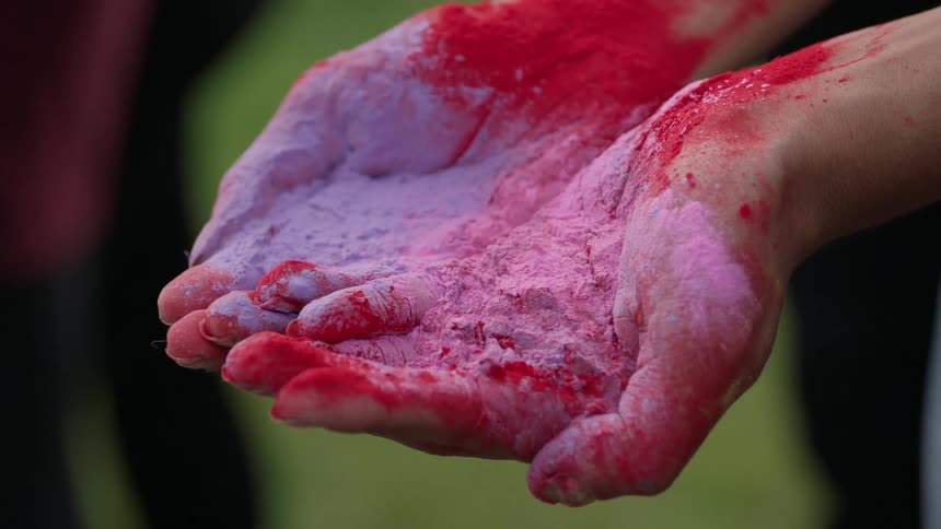Hands are covered in pink and purple powder