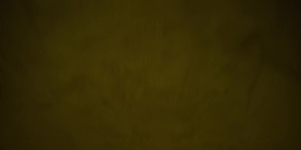 Point of view footage looking up while driving through a long, dark, and hazy tunnel as yellow ceiling lights pass overhead