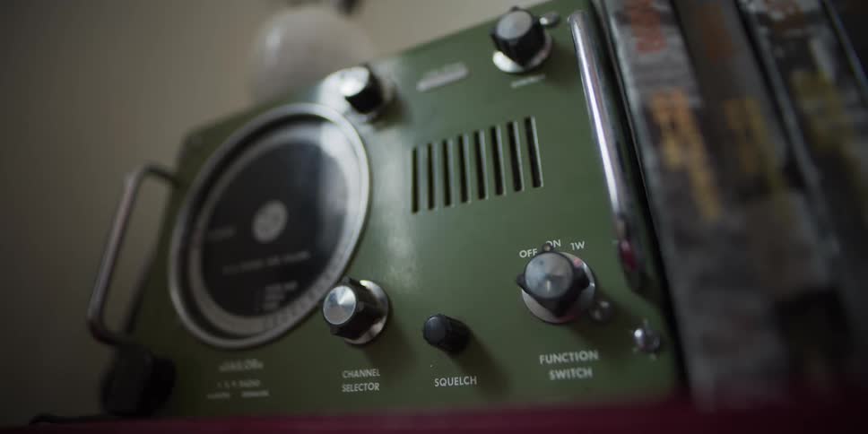 A slow rack focus across the dials and switches of a vintage green Sailor VHF marine radio