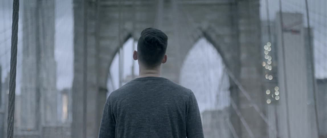 A man walks across a city bridge