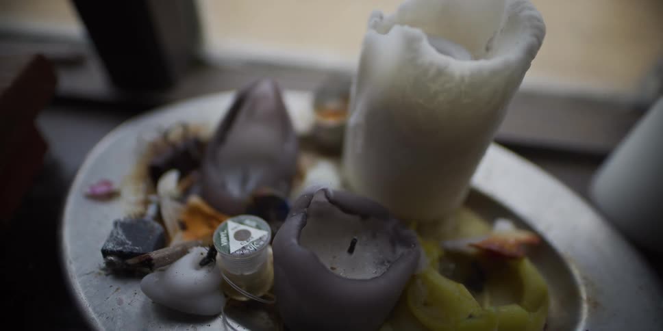 A slow zoom-out reveals a creepy altar with melted, burnt-out candles and other strange objects on a silver plate