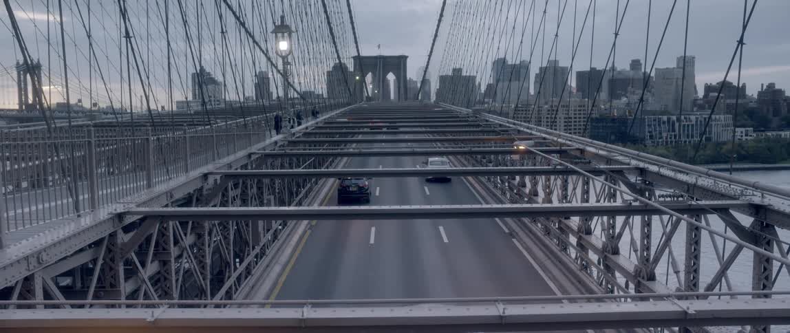 Cars driving over a bridge to get to a large city