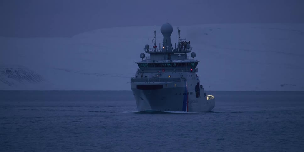 A formidable Coast Guard patrol ship navigates through the serene, twilight waters of the Arctic