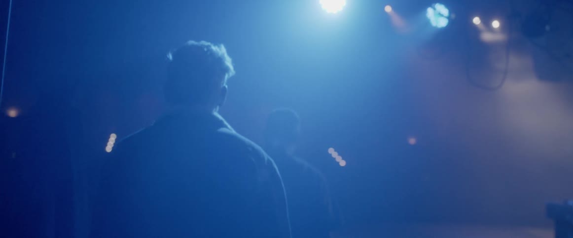 Man walks onto a brightly lit stage
