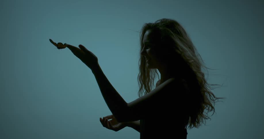 A butterfly flies from a woman's hand