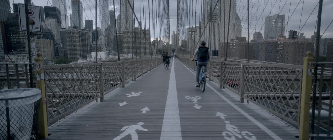 People commuting by foot or bike on a city bridge