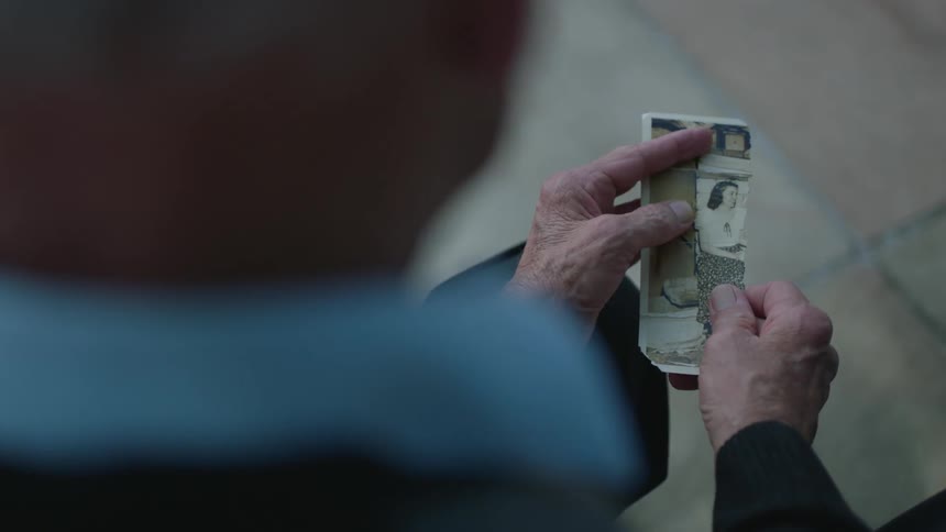 Older person unfolds a torn photograph