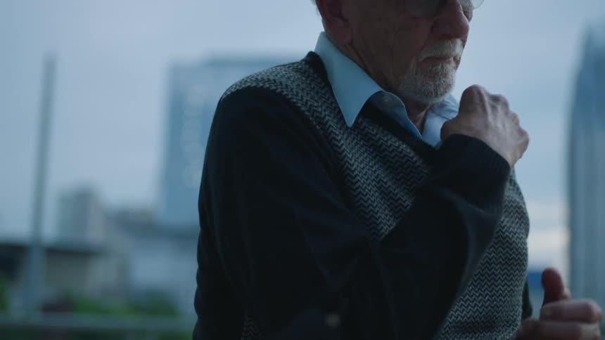 An elderly man pulls a photograph from his vest
