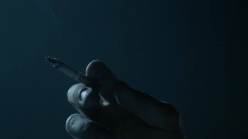 A person flicks the ashes off their cigarette