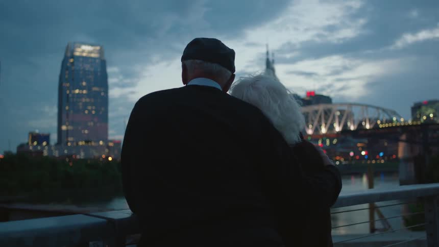 A man and woman hug by the view of a city at dawn