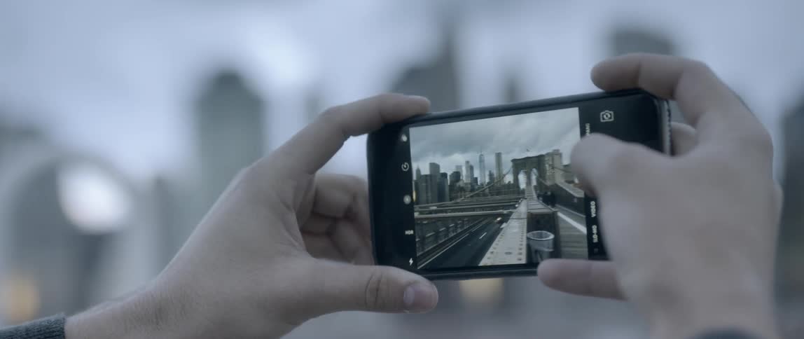 A person recording traffic passing over bridge with their phone