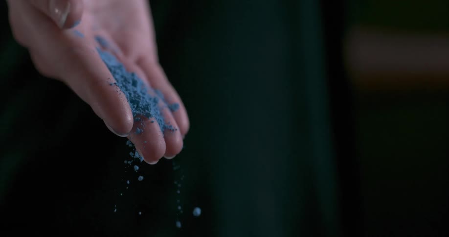 Blue powder falls off of a hand