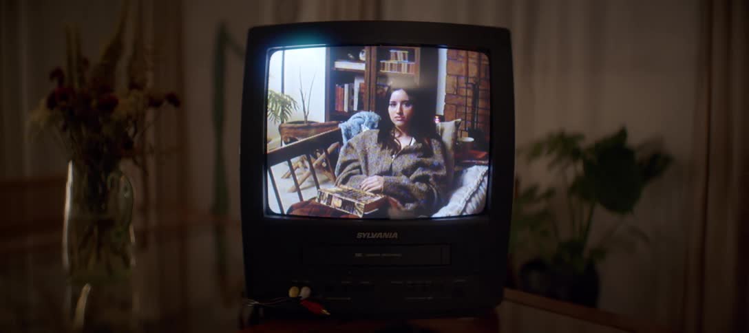 A nostalgic home video of a woman plays on a retro CRT television with a built-in VCR