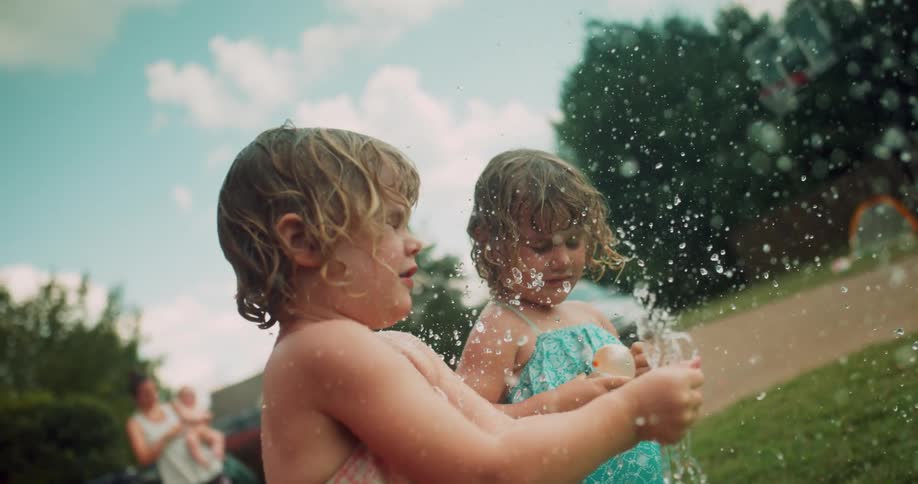 Two children play with water balloons in the park