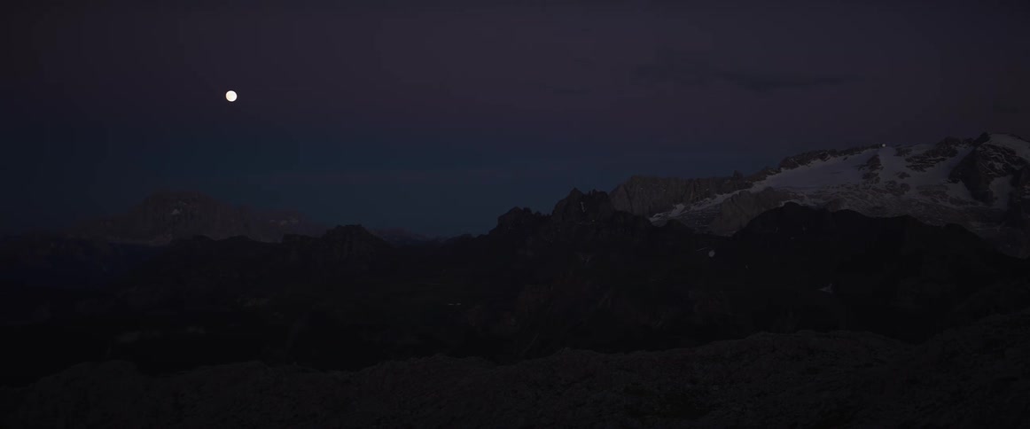 A timelapse of the full moon rising over the Dolomites as the vibrant sunset sky transitions to night