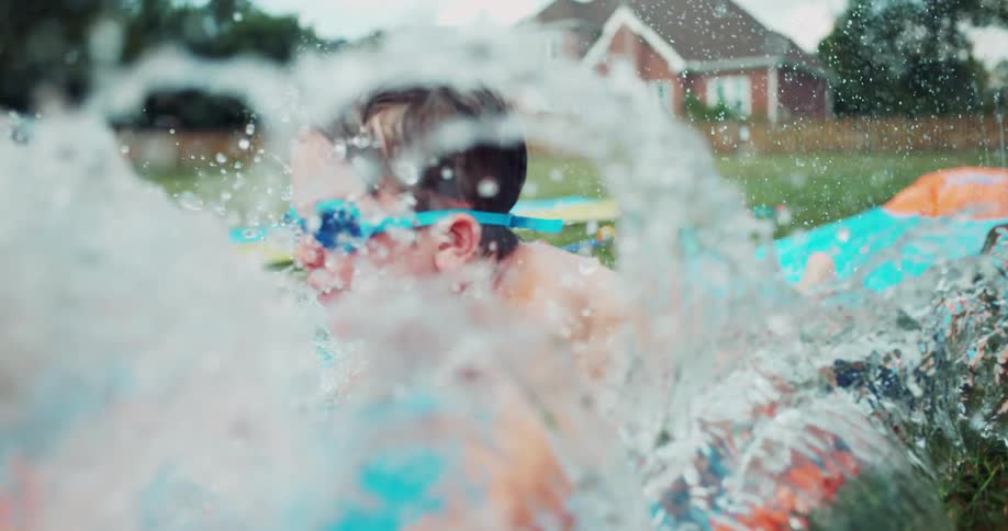 Boy slides down a slip n' slide on a sunny day
