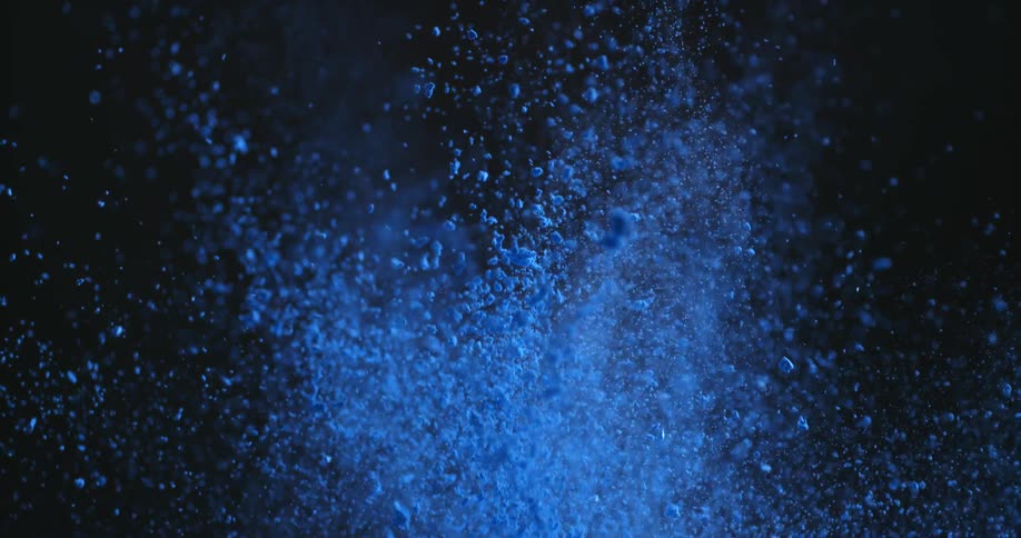 Blue powder puffs into the air in a dark room