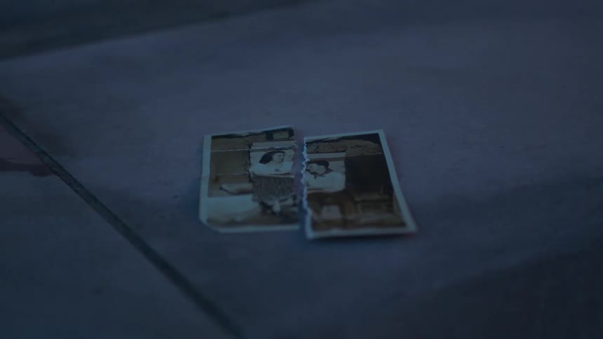 A torn photograph lays on a ledge