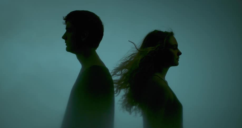 A man and woman turn back to back on a windy day