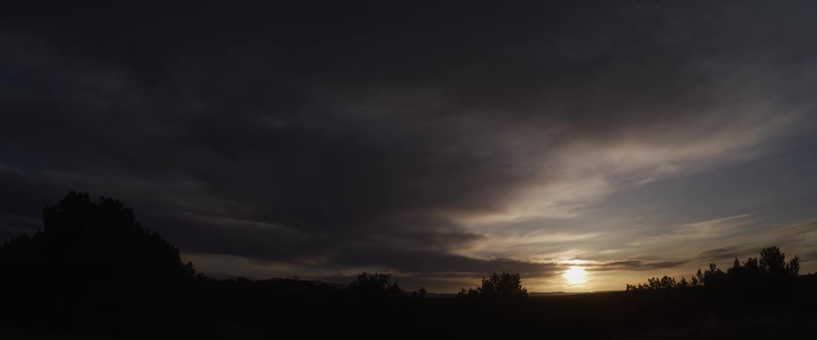 A dramatic time-lapse captures the sun breaking through dark, moody clouds at sunrise