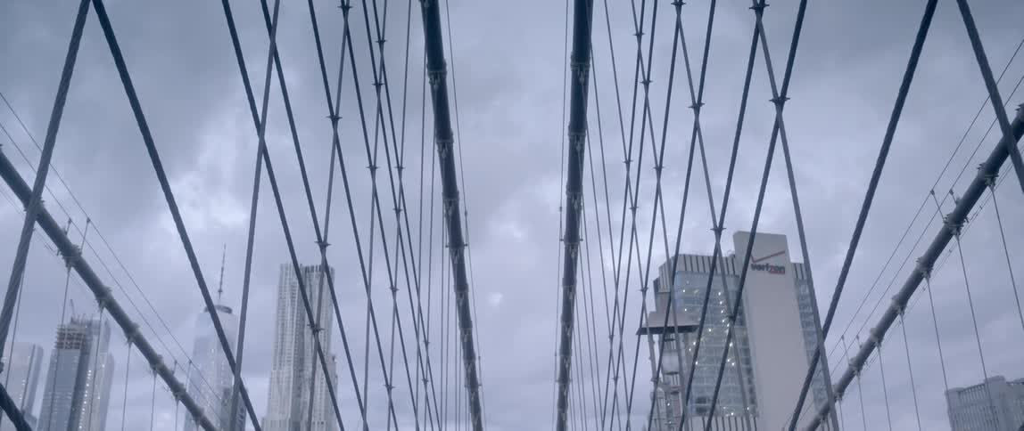 Three people walk down the side of a bridge