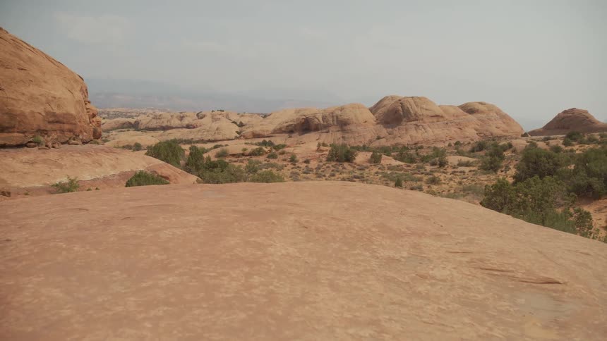 A static wide shot showcases the vast and arid landscape of a rocky desert with unique sandstone formations