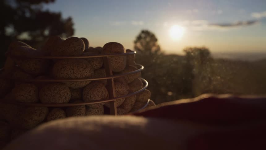 Steam rises from hot sauna rocks in slow motion with a beautiful sunset view in the background