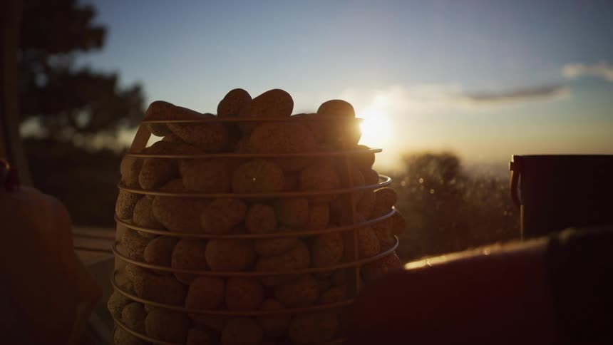 Water is thrown on hot sauna stones in slow motion, creating steam as the sun sets in the background