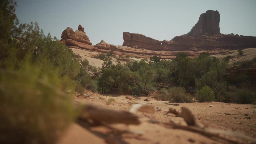 A stunning wide-angle view from a low perspective reveals the vast, arid desert landscape of Utah, with towering red rock formations in the distance