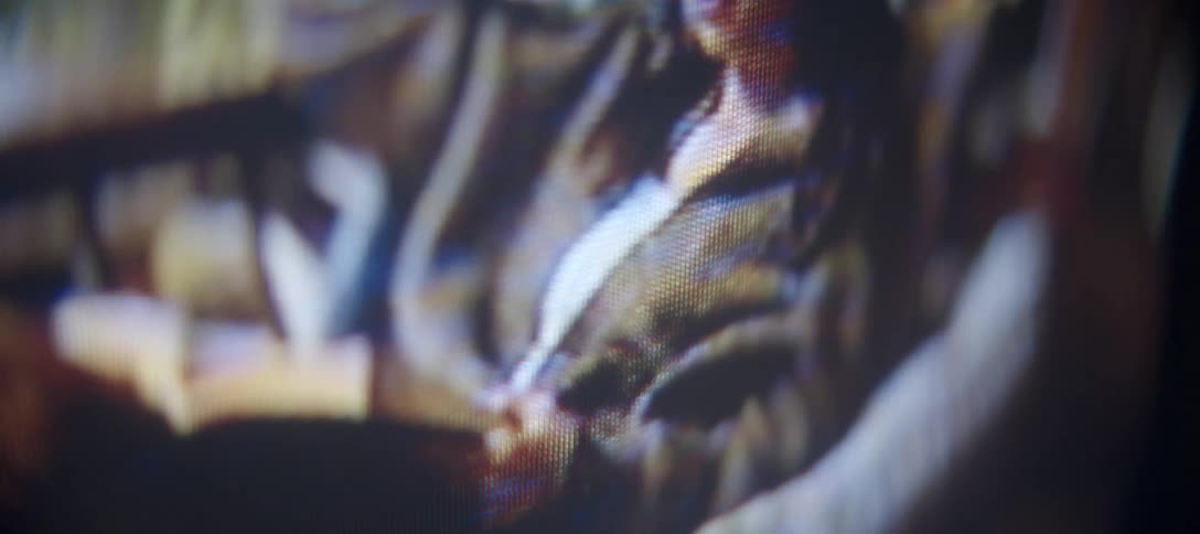 An abstract and blurry close-up captures the pixelated image of a woman relaxing on a screen