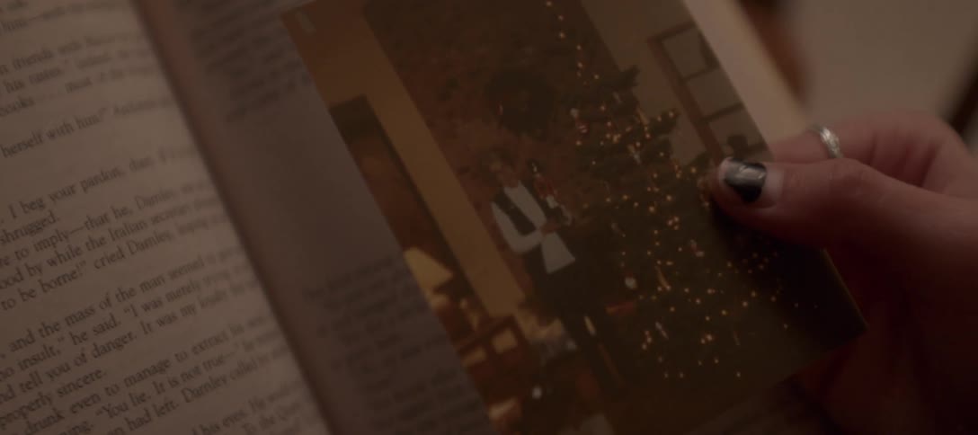 A person holds a vintage photograph of a cherished Christmas memory over an open book
