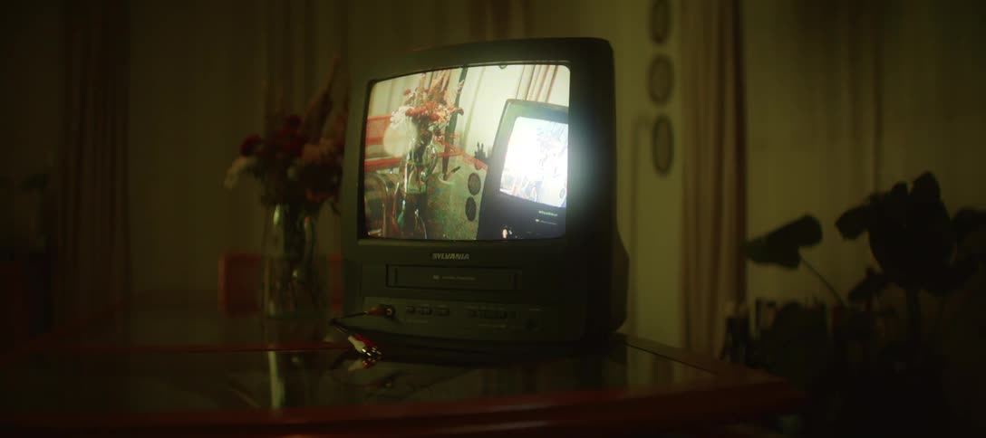 Mysterious shot zooms into a retro television displaying an infinite feedback loop as the room's lighting changes colors
