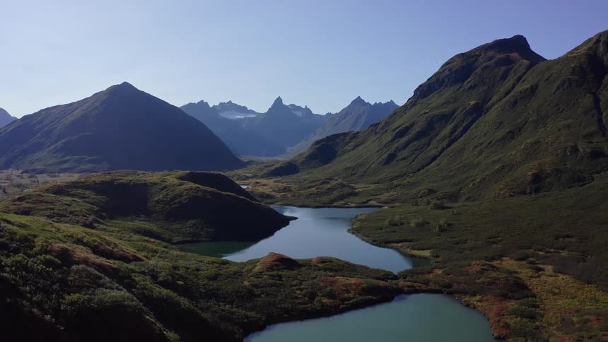 A static aerial view of the breathtaking and remote Alaskan wilderness, featuring serene lakes and a majestic mountain range