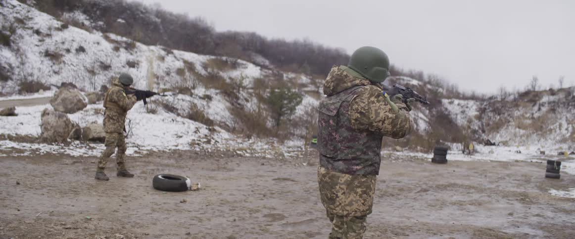 Slow motion shot of a Ukrainian soldier firing an assault rifle during training exercises at a winter range