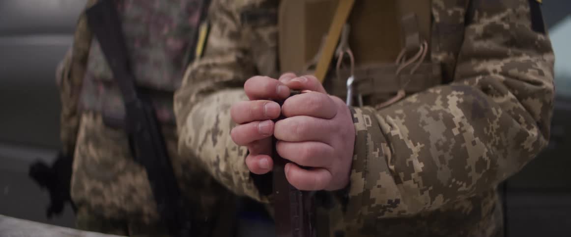 A soldier in a camouflage uniform loads bullets into a rifle magazine in slow motion