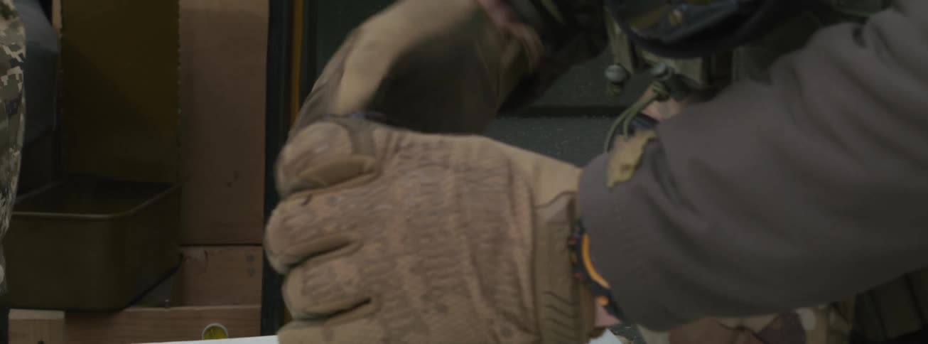 Soldier in camouflage receives bullets and loads them into a gun magazine one by one