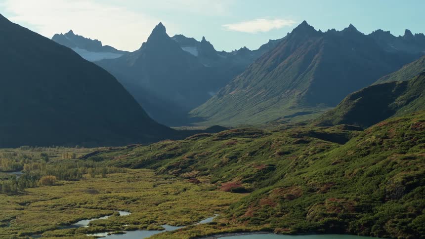 An epic aerial journey through a pristine mountain valley with a winding river and lush green hillsides